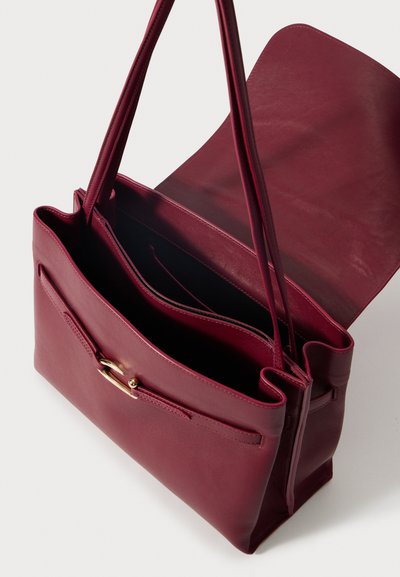 Burgundin väri nahkakäsilaukku, jossa on kaksi kahvaa, sileä pinta ja kultasävytetty varustus. Auki oleva yläosa paljastaa sisäiset taskut.