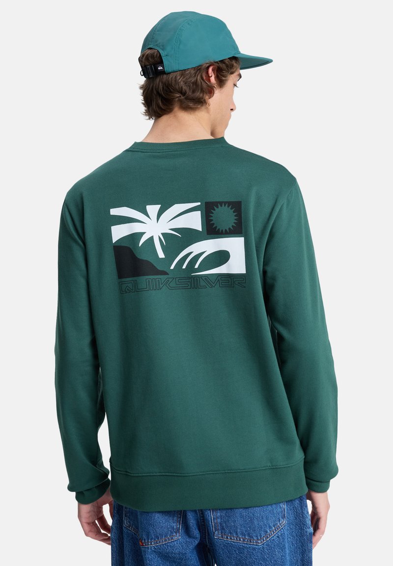 Sudadera verde con un estampado gráfico de palmeras, montañas y sol. Está hecha de una tela suave con puños y dobladillo acanalados.
