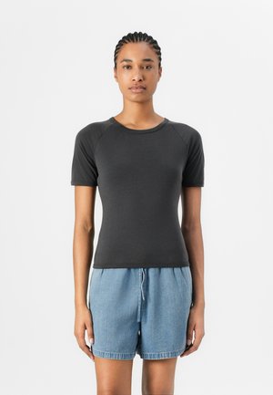Svart kortermet t-skjorte i en tettsittende design med rund hals og ribbet tekstur, kombinert med lyse denimshorts.