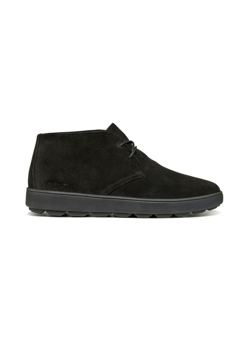 Botas de tobillo de ante negro con una textura suave, puntera redondeada y un diseño minimalista. Presentan una suela de goma negra con patrones de tracción.