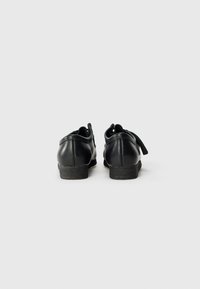 Pantofi negri din piele cu o textură netedă, cu toc rotund și talpa joasă din cauciuc; caracteristicile includ șireturi și accente de design minime.