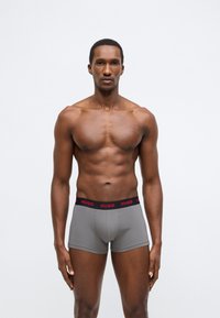 Γκρι boxer briefs με μαύρη μέση που φέρει κόκκινο λογότυπο "HUGO". Λείο ύφασμα, εφαρμοστή σχεδίαση, μήκος πάνω από το γόνατο.