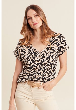 Zwarte top met een lichtbeige dierenprint en korte mouwen, met een V-hals en subtiele plooien, gecombineerd met beige broek en een gevlochten riem.