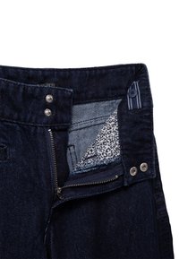 Ciemnoniebieskie dżinsy z zamkiem błyskawicznym, z metalowymi elementami w kolorze srebrnym oraz wewnętrzną podszewką w leopardzie wzory. Subtelne logo wzdłuż szwu bocznego.