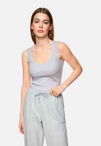Light gray fitted tank top with wide straps and a scoop neckline, paired with light gray drawstring trousers. Soft cotton blend material.
