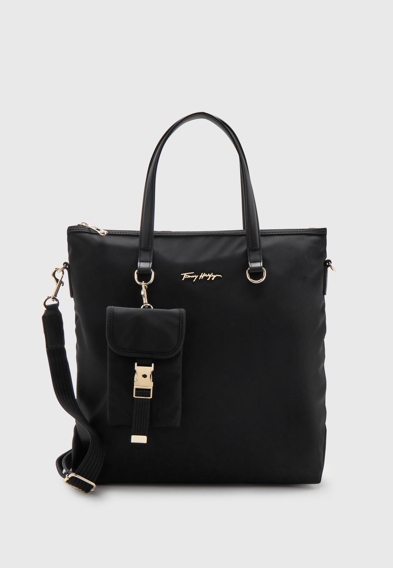 Sac cabas noir Tommy Hilfiger avec doubles poignées, bandoulière amovible, petite pochette avant avec boucle et logo doré au centre avant.