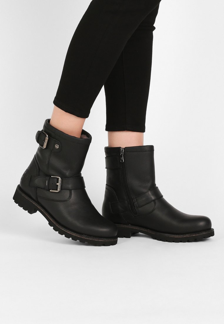 Bottines en cuir noir avec fermeture éclair sur le côté, accents de boucles et semelles texturées. Fini lisse avec un design robuste.