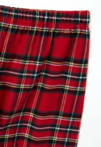 Tessuto di flanella rossa con un motivo tartan a quadri e una vita elasticizzata, probabilmente parte di un indumento come pantaloni da pigiama o pantaloncini.
