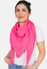 Écharpe en coton rose vif, texturée et triangulaire, drapée autour du cou, avec des extrémités arrondies et une finition froissée.