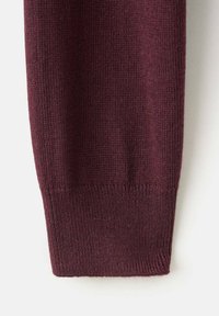 Manche de pull en maille bordeaux avec un poignet côtelé ; la texture est lisse et douce, affichant une couleur unie sans motifs ni accents.