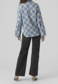 Ljusblå mönstrad skjorta med vita diamantformer, långa ärmar, ihopparad med svarta vida byxor och turkosa klackskor.