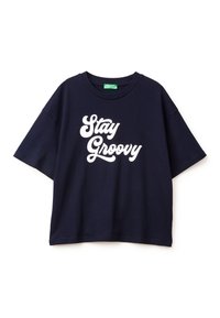 Námořnická modrá bavlněná tričko s kulatým výstřihem a krátkými rukávy. Bílé písmeno „Stay Groovy“ je napsáno tučným, hravým písmem.