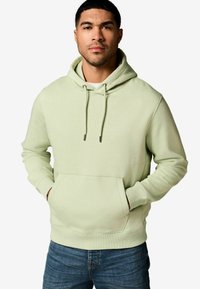Light green hoodie with a front pocket, drawstring hood, and ribbed cuffs. Paired with denim jeans. Soft fabric texture.