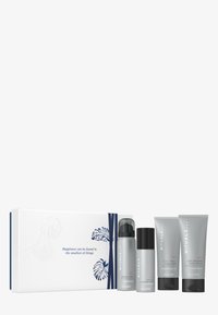 Zestaw czterech produktów do pielęgnacji skóry w szarych opakowaniach, w tym pianka pod prysznic, dezodorant i balsam do ciała, zaprezentowany w białym pudełku z niebieskimi akcentami.