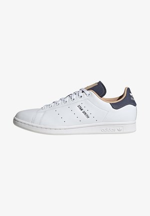 Baskets en cuir blanc avec un onglet de talon marine, des détails perforés sur les côtés, la marque "STAN SMITH" et une semelle en caoutchouc blanc. Design classique, style basse.