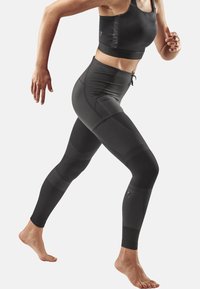 Black athletic leggings with varying textures and smooth finish, featuring a high waistband and an adjustable drawstring.