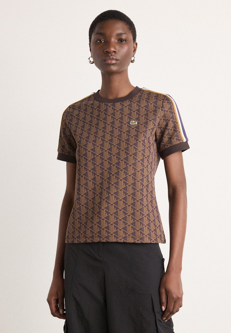 Braun Kurzarm-T-Shirt mit geometrischem Muster, kontrastierendem dunklem Kragen und Bündchen sowie Lacoste-Logo auf der Brust.