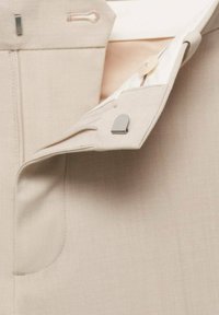Beige hlače iz tkanine z gladko teksturo, z zadrgo in gumbom. Vključuje siv akcentni kos in notranjo podlogo.