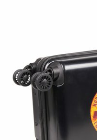 Valigia rigida nera con ruote doppie, caratterizzata da un design circolare. Include una zip lungo il bordo e un logo colorato sulla parte anteriore.