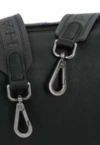 Borsa in pelle nera con finitura testurizzata, manici in tessuto grigio e ganci girevoli in argento attaccati a anelli metallici vicino a una cerniera.