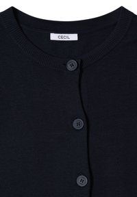 Cardigan en tricot noir avec un col rond, trois boutons sur le devant et une étiquette blanche portant l'inscription "CECIL" au niveau du col.