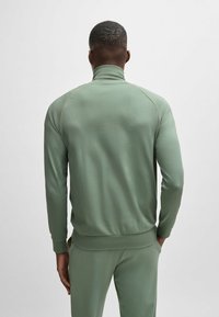 Lichtgroene, lange mouwen sporttrui met een hoge kraag, strakke pasvorm en contrasterende naden, gemaakt van zacht, rekbaar materiaal.