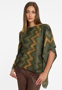 Poncho en bronze et vert à motifs zigzag, avec un large col et une coupe ample, fabriqué à partir d'un tissu métallisé doux et texturé.