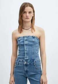 Stropfri denimtop med lodrette sømme, lyseblå farve, tekstureret stof, parret med matchende denimbunde, enkel sølvkæde halskæde.