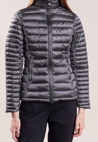 Dunkelgraue wattierte Jacke mit hohem Kragen, horizontalem Steppdesign, Reißverschluss und Seiten Taschen. Glatte, glänzende Stofftextur.