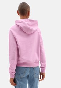 Sweat à capuche rose clair avec cordon de serrage, poignets et ourlet côtelés, vu de dos, assorti à un pantalon en denim bleu clair.