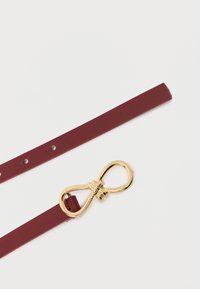 Bordowy skórzany pasek o gładkiej teksturze. Posiada złotą klamrę w kształcie nieskończoności z misternymi detalami.