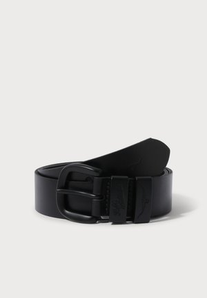 Ceinture en cuir noir roulée avec boucle noire mate et deux passants, l’un embossé d’un logo longhorn et l’autre avec du texte.