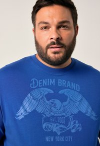 Královsky modré bavlněné tričko s potiskem orla a nápisem "DENIM BRAND EST. 2007 NEW YORK CITY" ve světle modré barvě.