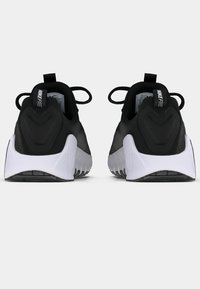 Μαύρα αθλητικά παπούτσια με κομψό σχεδιασμό, υφή στην επάν�ω επιφάνεια και αντίθετες λευκές σόλες με ευλύγιστο ελαστικό πέλμα.