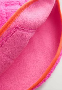 Fleece muts met een felle roze binnen- en buitenkant. Heeft een oranje rand langs de rand, met een zachte, textuurvolle materiaal.