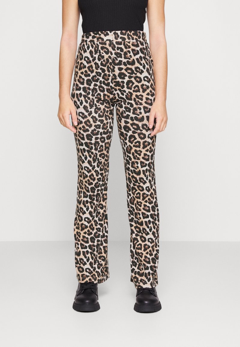 Pantalon imprimé léopard à taille haute, en tissu lisse. Ajusté à la cuisse et évasé à l'ourlet. Associé à des chaussures noires.