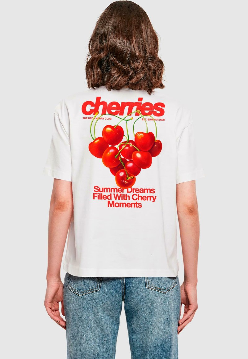 Vit t-shirt med en röd körsbärsgrafik på baksidan, tillsammans med texten "Sommarens drömmar fyllda med körsbärsmoments." Avslappnad passform.