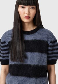 Hellblauer und schwarzer gestreifter Pullover mit einer weichen, flauschigen Textur, runder Ausschnitt und kurzen Ärmeln mit horizontalen schwarzen Streifen.
