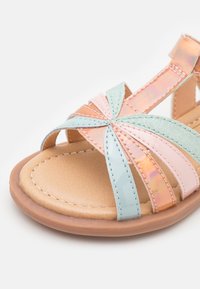 Sandalias con correas que presentan bandas en tonos pastel de rosa, verde e iridiscente, con una suela texturizada y acentos cosidos. Ajustables con una correa trasera.