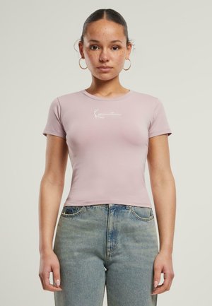 Kortsleeve, tettsittende t-skjorte i myk rosa bomull med rund hals og hvit tekstdesign, kombinert med høyt liv blå denimjeans.