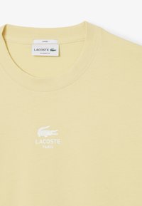 T-shirt gialla Lacoste con scollatura rotonda, caratterizzata da una stampa del logo bianco. Realizzata in morbido cotone con un design a vestibilità classica.