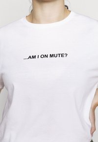 Valkoinen puuvillapaita, jossa on musta teksti "...OLEMMEKO MUTEISSA?" painettuna rinnan kohdalle. Klassinen pyöreä pääntie.