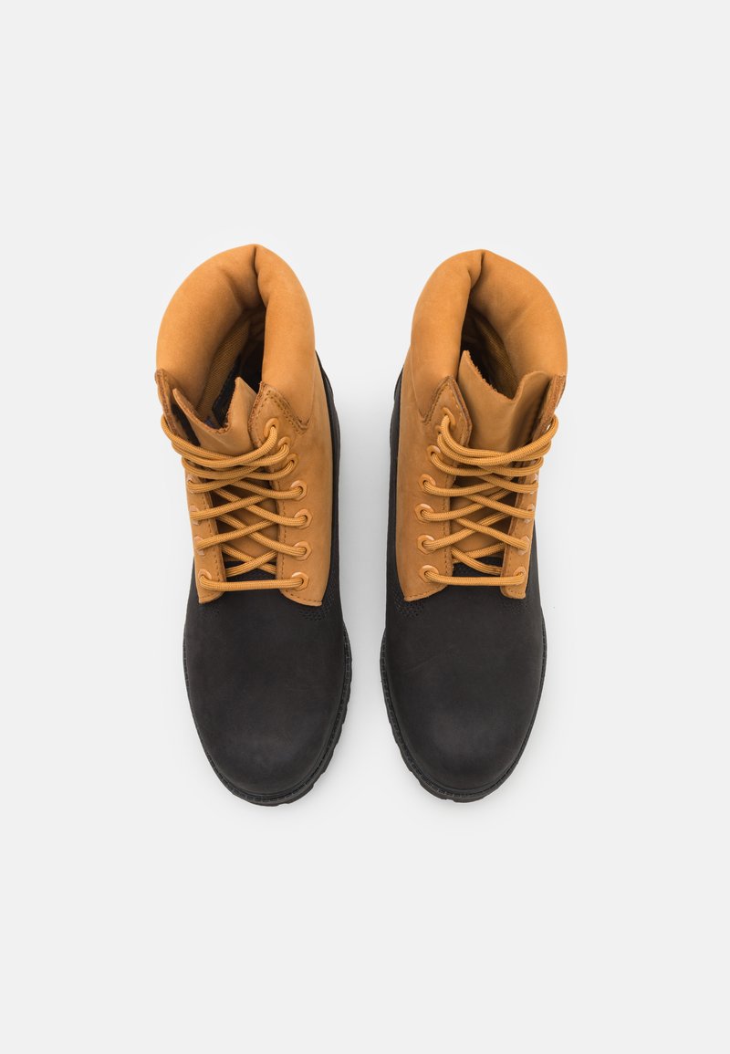 Bottes à lacets noires et brunes avec une tige lisse, un col rembourré, une semelle en caoutchouc et des lacets contrastants, présentant un design et une texture robustes.