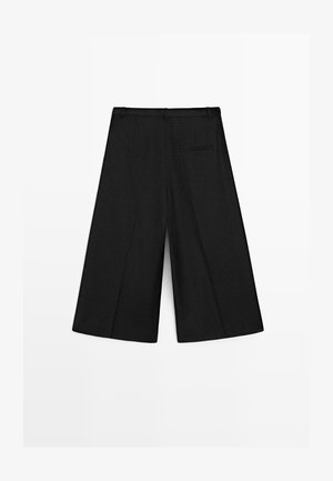 Schwarze Culotte-Hose mit weitem Bein, Gürtelschlaufen und einer einzelnen Paspeltasche hinten, flach auf weißem Hintergrund präsentiert.