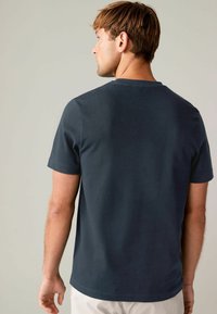 Dunkelblaues Baumwoll-T-Shirt mit Rundhalsausschnitt, kurzen Ärmeln und lockerem Schnitt. Glatte Textur und schlichtes Design, keine Muster oder Akzente.