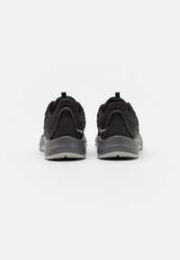 Scarpe sportive nere con parte superiore in tessuto a rete, dettagli riflettenti, colletto e linguetta imbottiti, suola grigia chiara e inserto posteriore per indossarle facilmente.