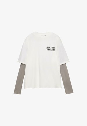 Bijela pamučna majica opuštenog kroja, s dugim sivim rukavima. Na prednjoj strani crnim slovima piše "DANCE FIRST THINK LATER".