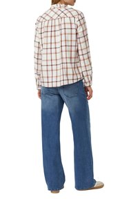 Geruite blouse met lange mouwen in wit, beige en mauve met een geplooide achterkant. Gecombineerd met losse, blauwe jeans en witte sneakers.