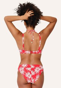 Červené bikiny s bielymi vzormi palmových listov, s halter krkom a viazaním, nastaviteľným uzáverom na chrbte a štruktúrovanou tkaninou.