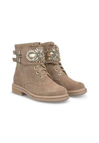 Stivaletti alla caviglia in suede beige con sole piatta, lacci sul davanti e polsini decorativi con perline che presentano motivi floreali e accenti metallici.